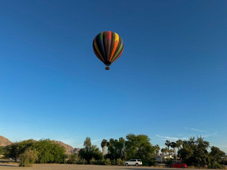 Hot air balloon floating above Coachella Valley desert at dawn