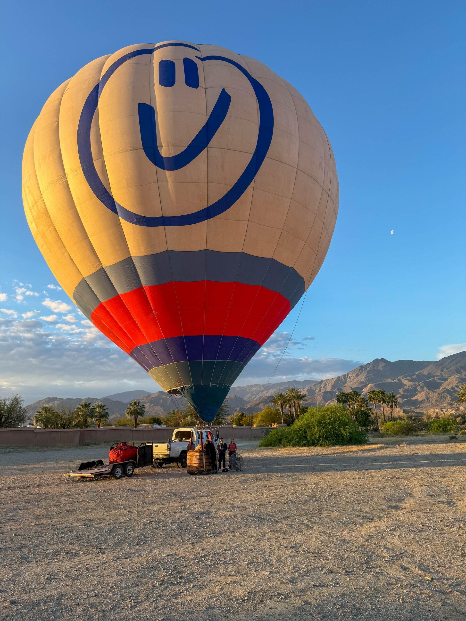 Colorful hot air balloon drifting over Coachella Valley at sunrise
